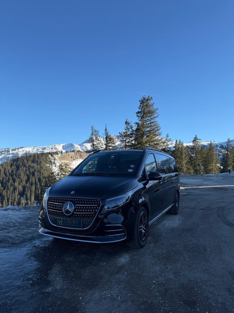Van de luxe Mercedes-Benz Classe V noir avec chauffeur, dans une station de ski enneigée des Alpes françaises.