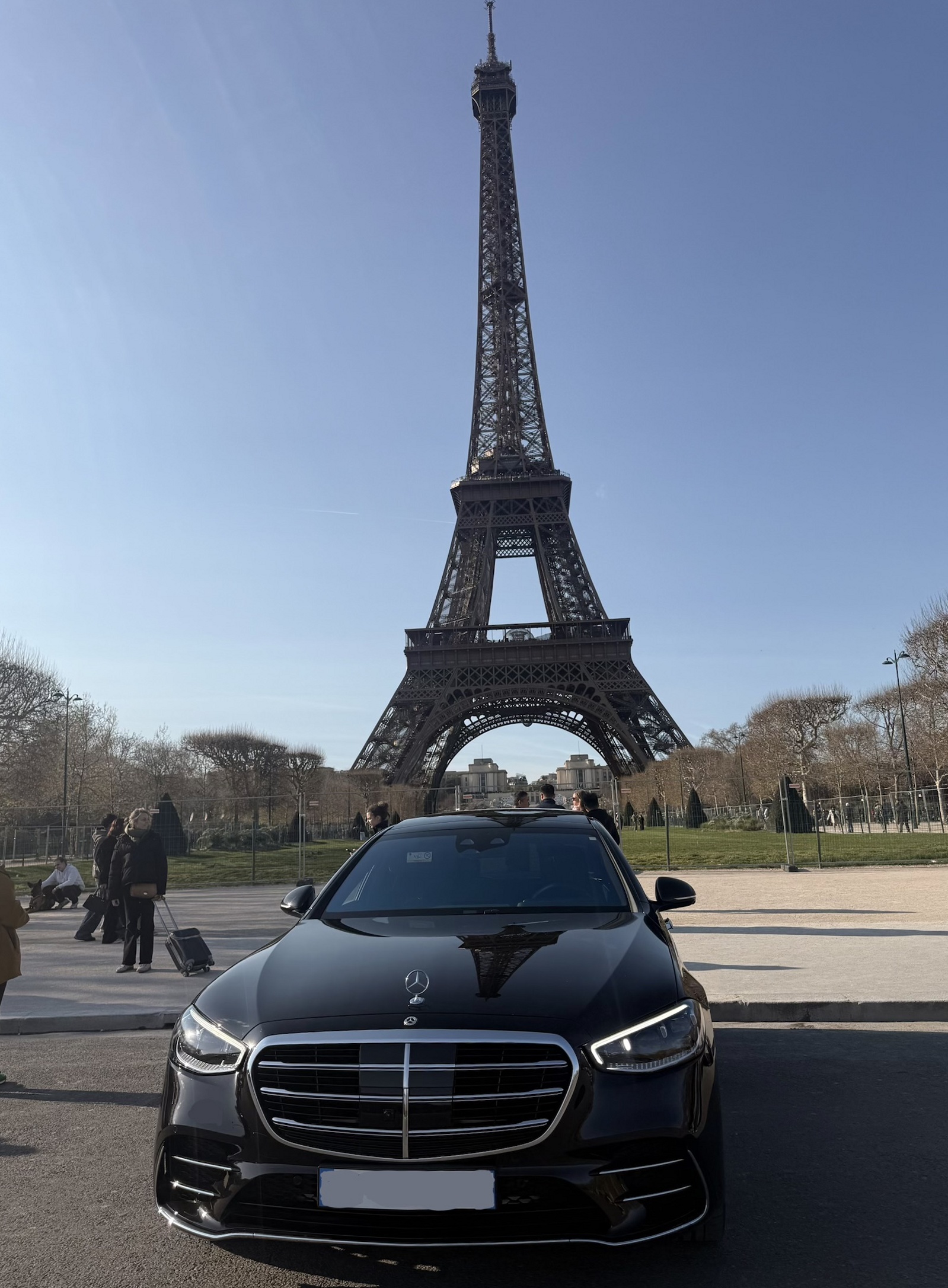 Berline de luxe Mercedes-Benz Classe S noire avec chauffeur, Tour Eiffel visible à Paris.